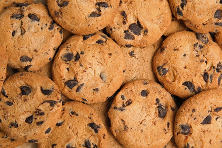 Tasty chocolate chip cookies as background, top view