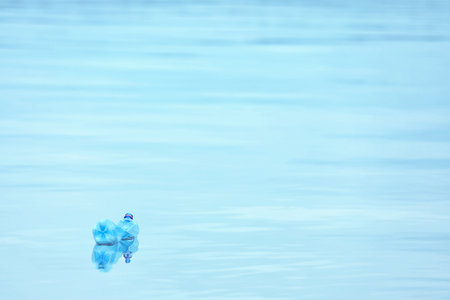 Used plastic bottle floating on water surface, space for text. recycling problemの写真素材