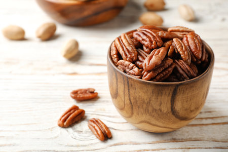 Tasty pecan nuts in a dish on a wooden table. Space for text