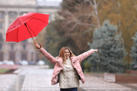 Woman with umbrella in city on autumn rainy dayの写真素材
