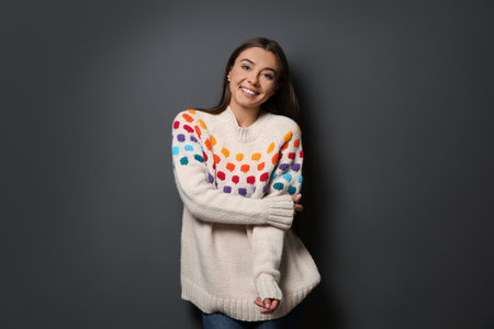 Beautiful young woman in warm sweater on dark backgroundの写真素材