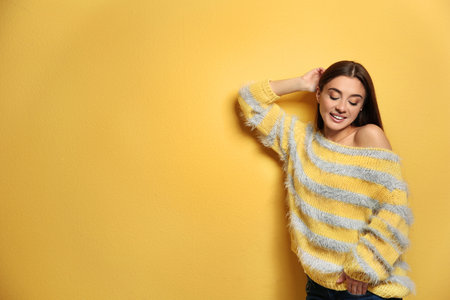 Beautiful young woman in warm sweater on color background. Space for textの写真素材
