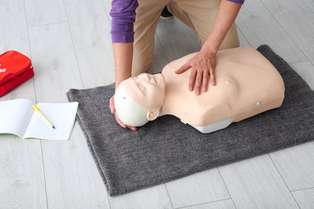 Man practicing first aid on mannequin indoors, closeup