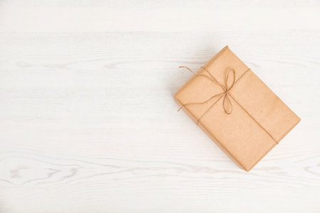 Parcel decorated with twine and space for text on wooden background, top view