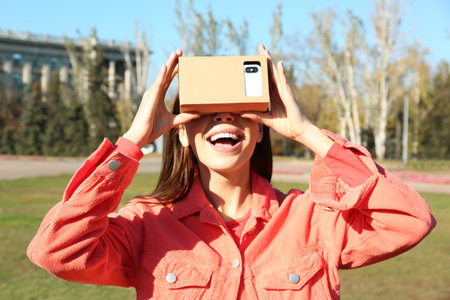 Young woman using cardboard virtual reality headset outdoorsの写真素材