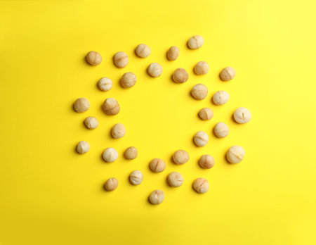 Frame made of shelled organic Macadamia nuts on color background, top view. Space for text