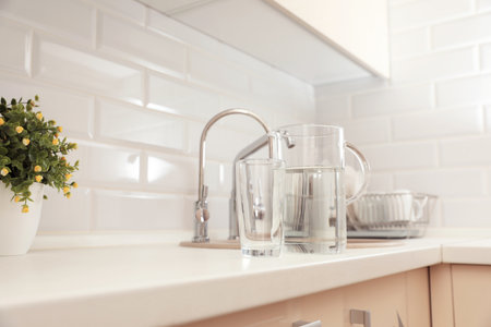 Jug and glass with water on table in kitchenの写真素材