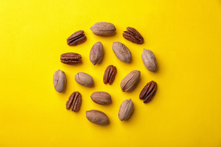 Composition with pecan nuts on color background, top view