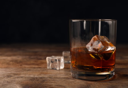 Golden whiskey in glass with ice cubes on table. Space for textの写真素材