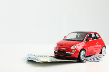 Toy car and money on white background, space for text. vehicle insuranceの写真素材