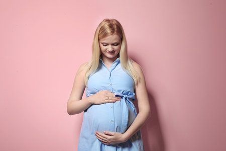 Beautiful pregnant woman in dress on color backgroundの写真素材