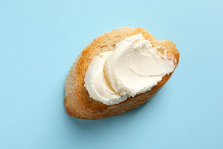Piece of baguette with tasty cream cheese on color background, top viewの写真素材