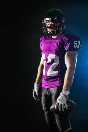 American football player with ball on dark backgroundの写真素材