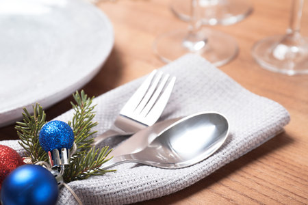 Cutlery, napkin and Christmas decor on wooden background, closeup. Festive table setting