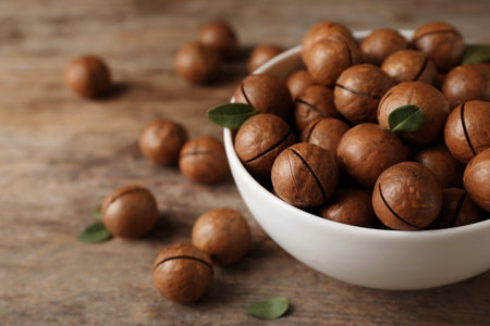 Bowl with organic Macadamia nuts and space for text on wooden backgroundの写真素材