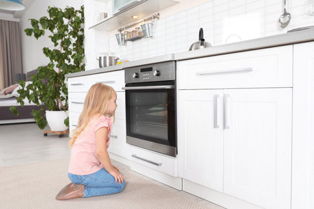 Little girl baking something in the oven at homeの写真素材
