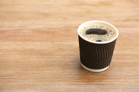Cardboard cup of coffee on wooden table. Space for textの写真素材