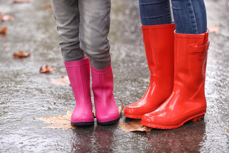 Mother and daughter wearing rubber boots after rain, focus of legs. autumn walkの写真素材