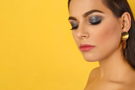 Portrait of beautiful woman with stylish makeup on color background. Space for textの写真素材