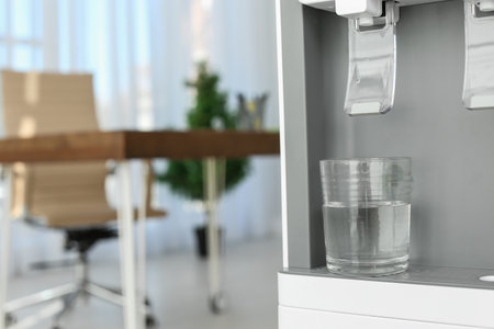 Modern water cooler with glass in office, closeup. Space for textの写真素材