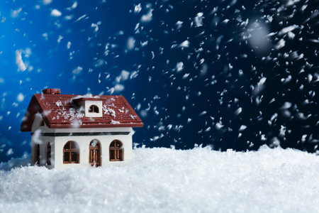 Decorative house in snowdrift on color background, space for text. Winter weatherの写真素材
