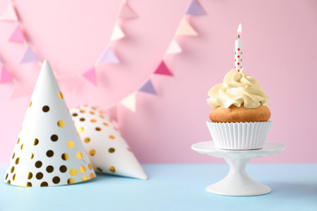 Dessert stand with delicious birthday cupcake on color backgroundの写真素材
