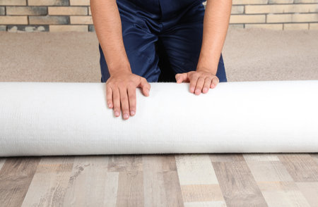 Man rolling out new carpet flooring indoors, closeupの写真素材