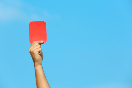 Football referee showing red card against blue sky, closeup with space for textの写真素材