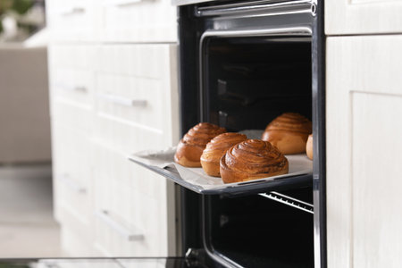 Open oven with tray of freshly baked buns in kitchen