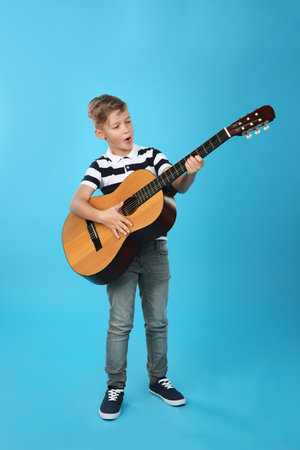 Little boy playing guitar on color backgroundの写真素材