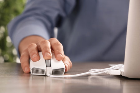 Man using computer mouse with laptop at table, closeupの写真素材