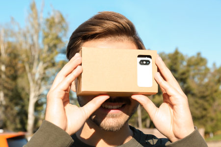Young man using cardboard virtual reality headset outdoorsの写真素材