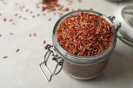 Brown rice in glass jar on table. Space for textの写真素材