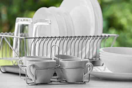 Set of clean dishes, glasses and cups on table against blurred backgroundの写真素材