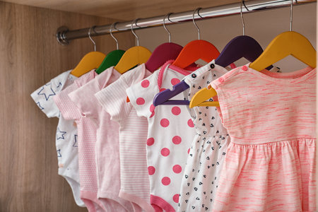 Hangers with baby clothes on rack in wardrobe, closeupの写真素材