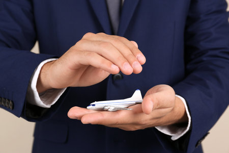 Insurance agent covering toy plane on color background, closeup. Travel safety conceptの写真素材