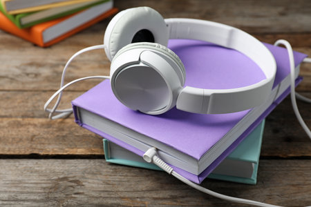 Modern headphones with hardcover books on wooden tableの写真素材