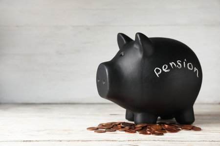 Piggy bank with word PENSION and coins on table. Space for textの写真素材