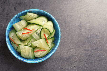 Dish with fresh cucumber salad on table, top view. Space for text