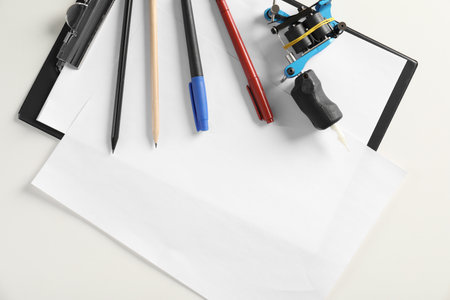 Composition with empty sheet of paper and tattoo machine on white background, top view. Space for textの写真素材