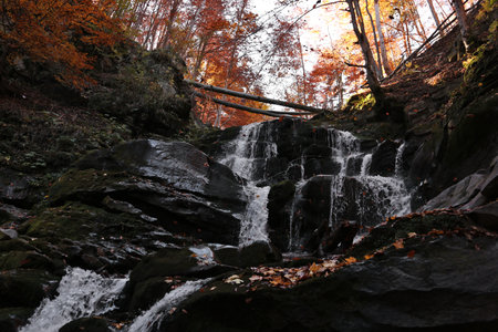 Beautiful waterfall with stones in autumn forest