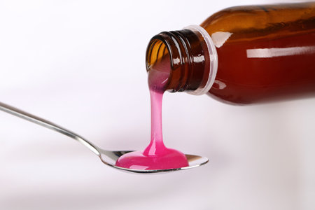 Pouring cough syrup into spoon on white background, closeupの写真素材