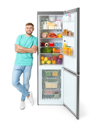 Young man near open refrigerator on white backgroundの写真素材