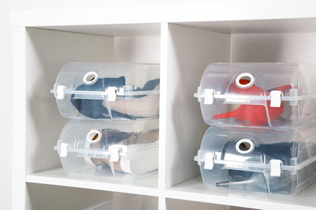 Footwear and plastic boxes on shelves near wall. Shoe storage organization