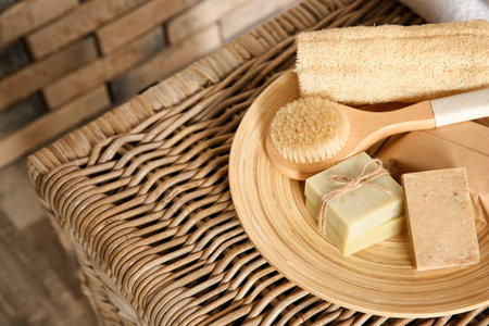 Plate with brush, wisp and handmade soap bars on wicker chest, closeup. Space for textの写真素材