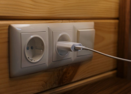 Charging plug with USB cable in socket on wall
