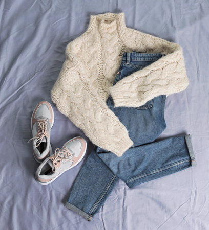 Flat lay composition with jeans, sweater and shoes on color fabricの写真素材