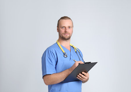 Portrait of medical assistant with stethoscope and clipboard on color background