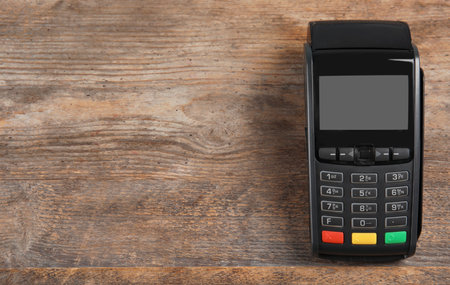 Modern payment terminal on wooden background, top view. Space for textの写真素材