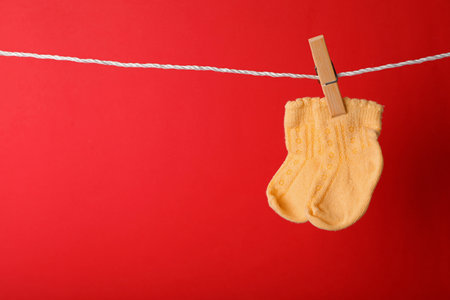 Cute child socks on laundry line against color background. Space for textの写真素材